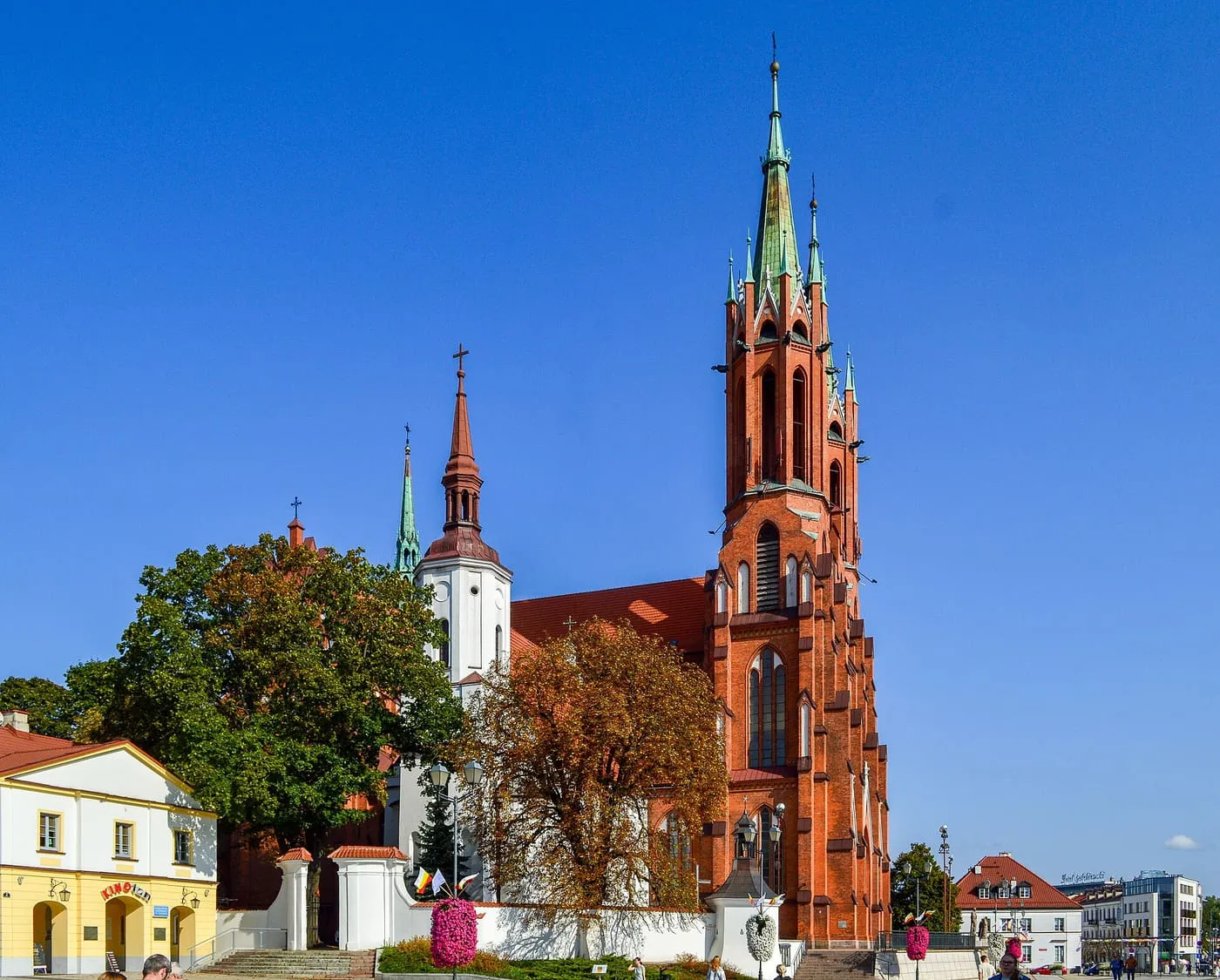 Neogotycka archikatedra w Białymstoku z czerwonej cegły, z wysoką wieżą zwieńczoną zieloną iglicą, obok starszego, białego kościoła