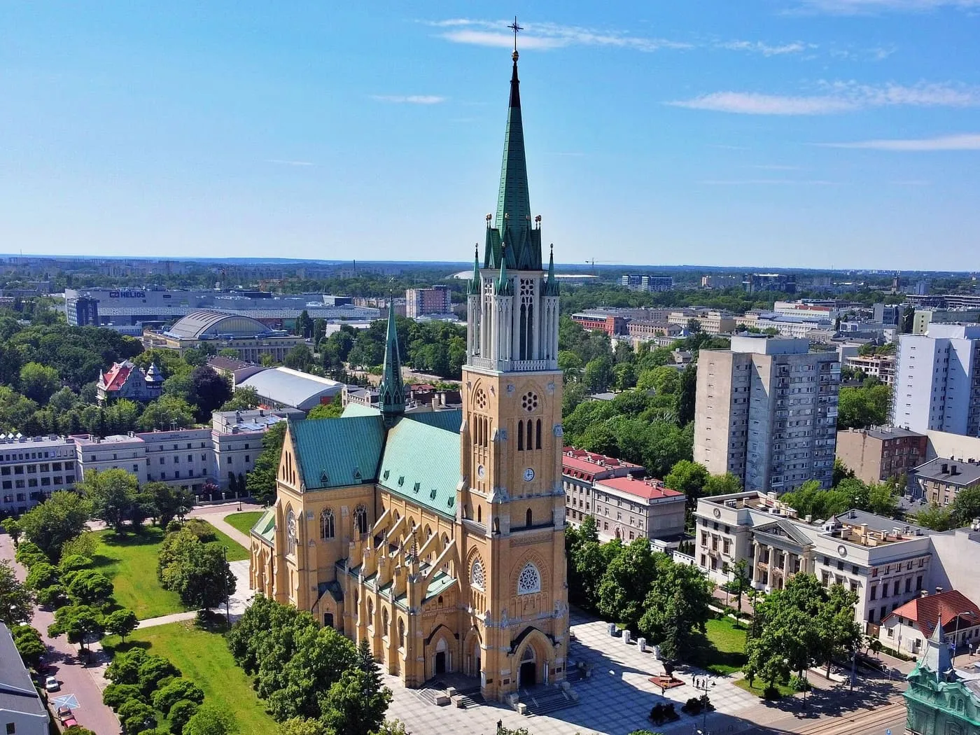Neogotycka archikatedra w Łodzi z lotu ptaka, z wysoką wieżą zwieńczoną zieloną iglicą pośród miejskiej zabudowy