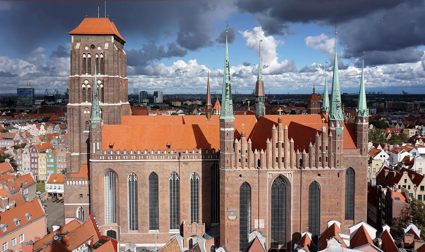 Bazylika Mariacka w Gdańsku, widok z lotu ptaka na masywną ceglaną budowlę z wieżą i smukłymi wieżyczkami na tle Starego Miasta