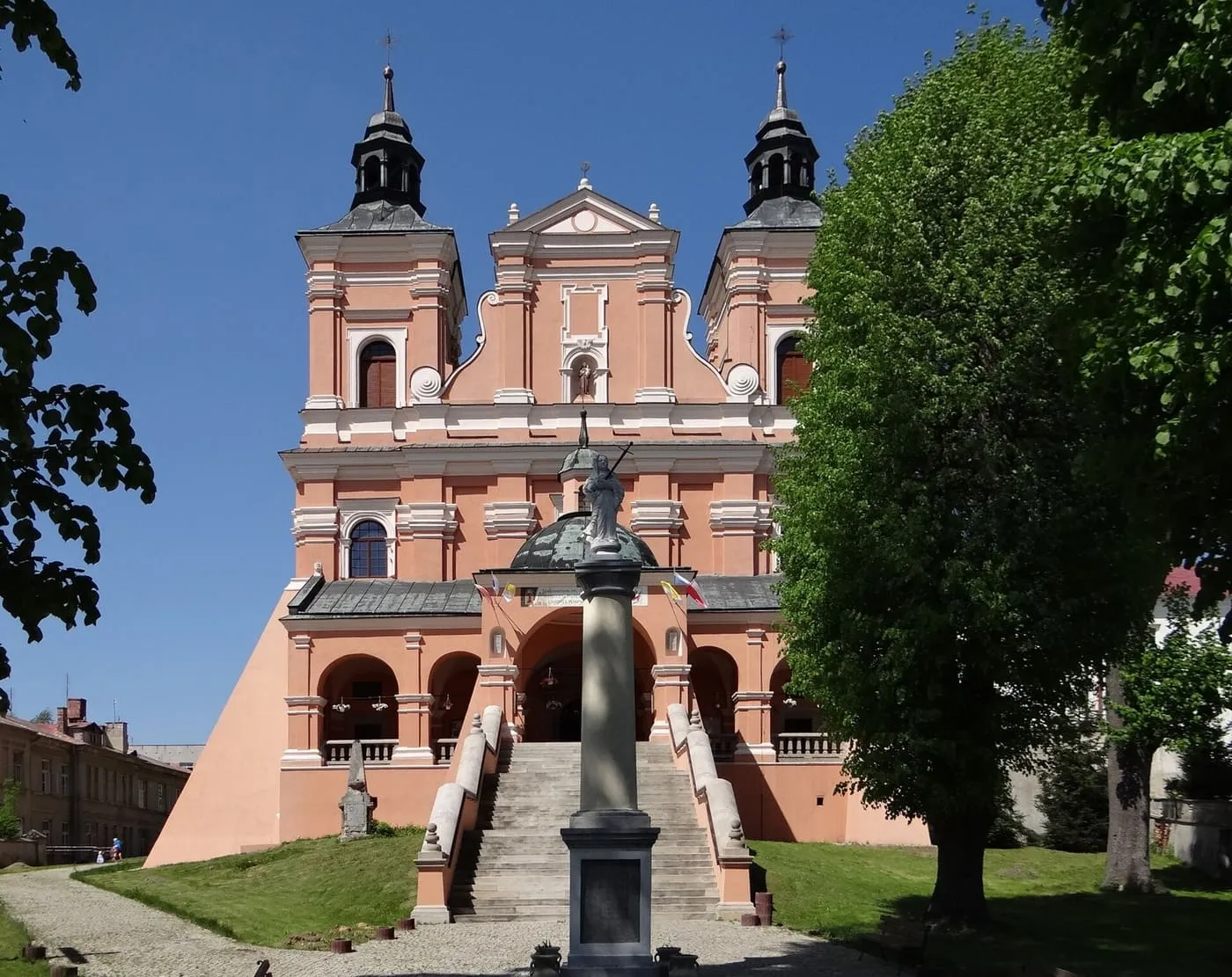 Różowa, barokowa bazylika św. Antoniego w Radecznicy z dwiema wieżami i figurą świętego na kopule