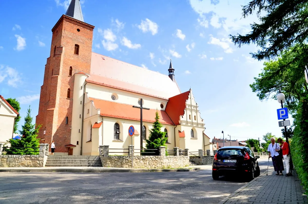 Ceglano-otynkowana bazylika św. Jana Chrzciciela w Krotoszynie z wieżą i czerwonym dachem nawy ze schodkowym szczytem