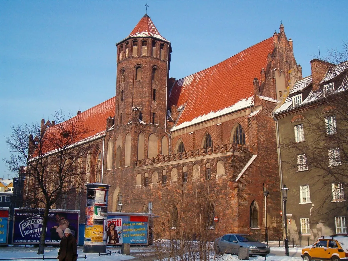 Ceglana, gotycka bazylika św. Mikołaja w Gdańsku z ośmioboczną wieżą i czerwonym dachem, zimą