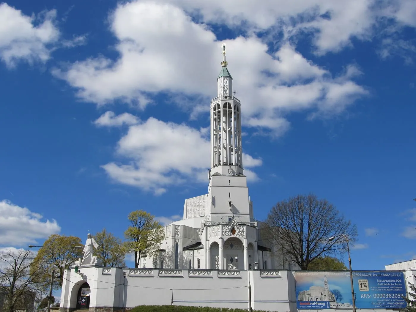 Biały, modernistyczny kościół św. Rocha w Białymstoku z ażurową wieżą wznoszącą się nad ośmioboczną bryłą