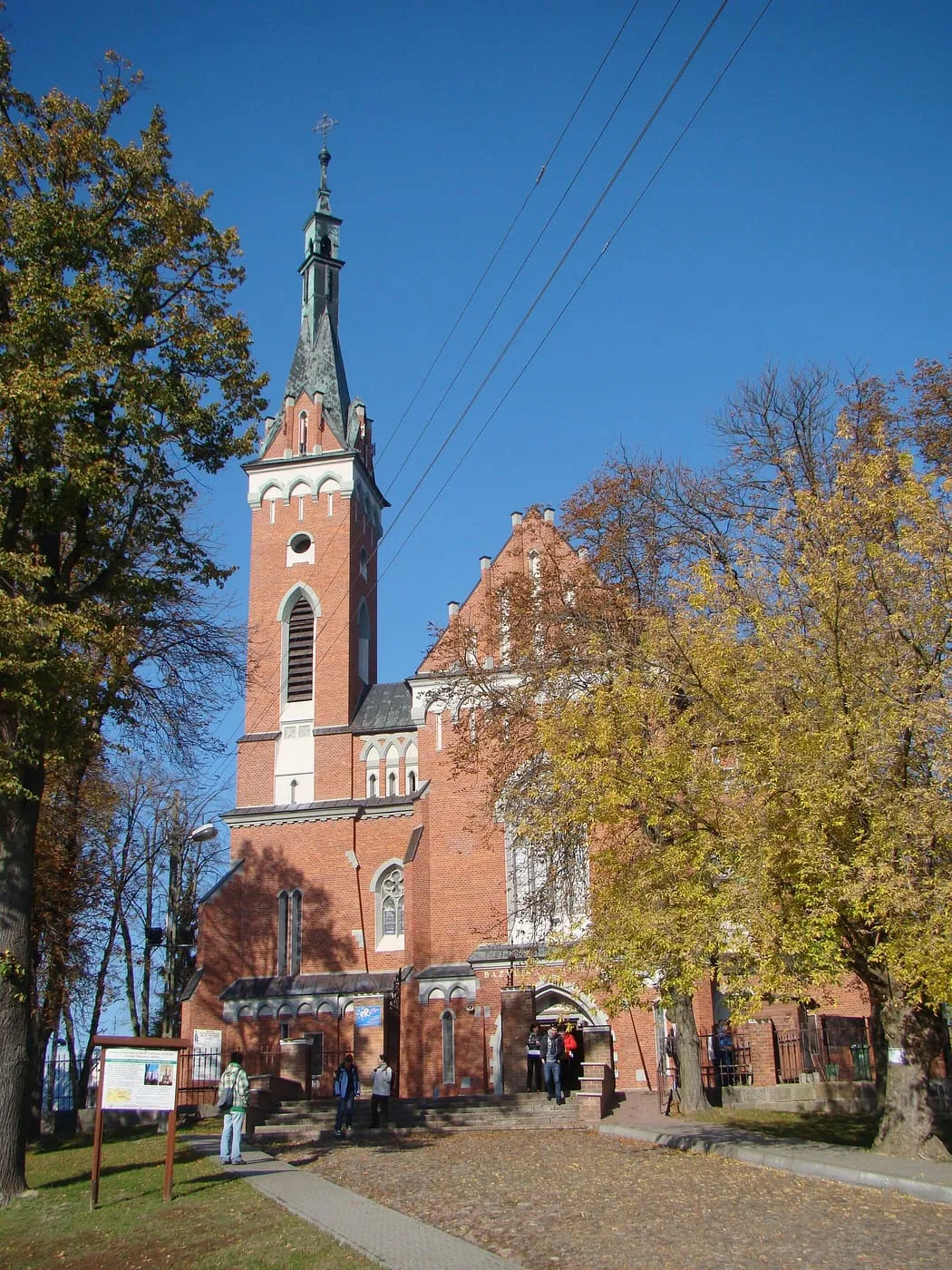 Neogotycka, ceglana bazylika św. Wojciecha w Wąwolnicy z pojedynczą wieżą zwieńczoną spiczastym hełmem