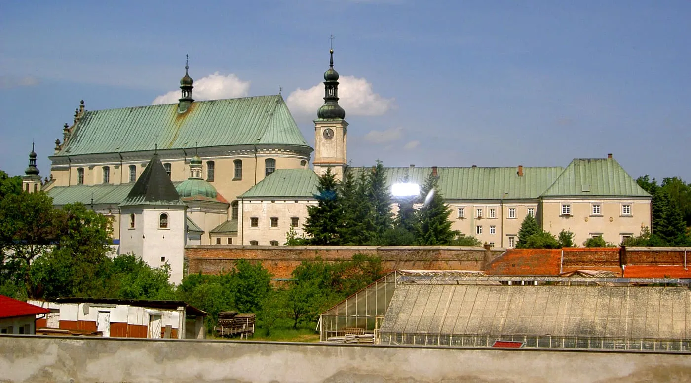 Zespół klasztorny bernardynów w Leżajsku widziany z oddali — kościół z miedzianym dachem i wieżą zegarową pośród zabudowań klasztornych
