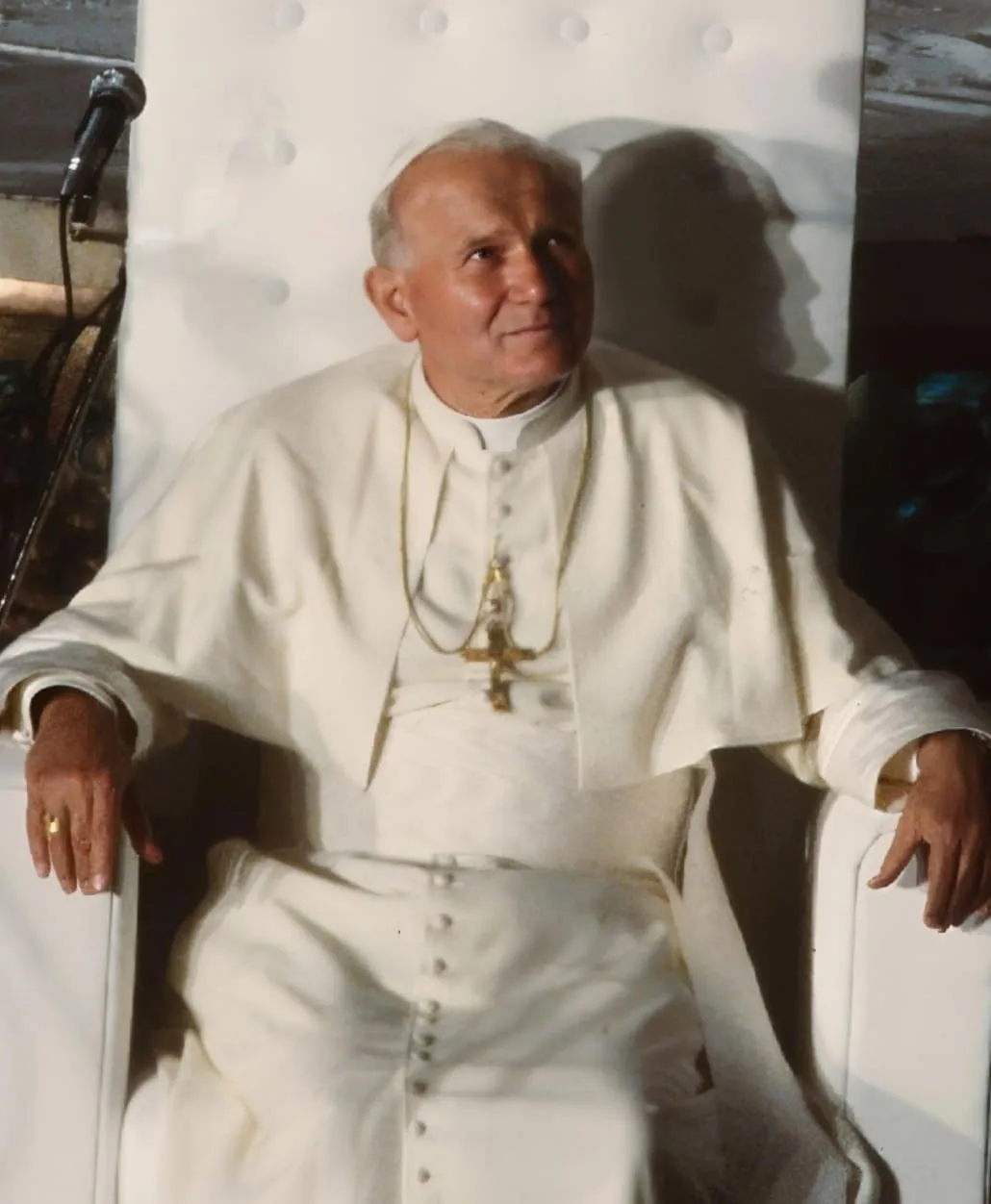 Fotografia Jana Pawła II z 1983 roku: papież w białej sutannie z pektorałem siedzi w białym fotelu i spogląda w górę z lekkim uśmiechem, wykonana w Katowicach podczas pielgrzymki do Polski