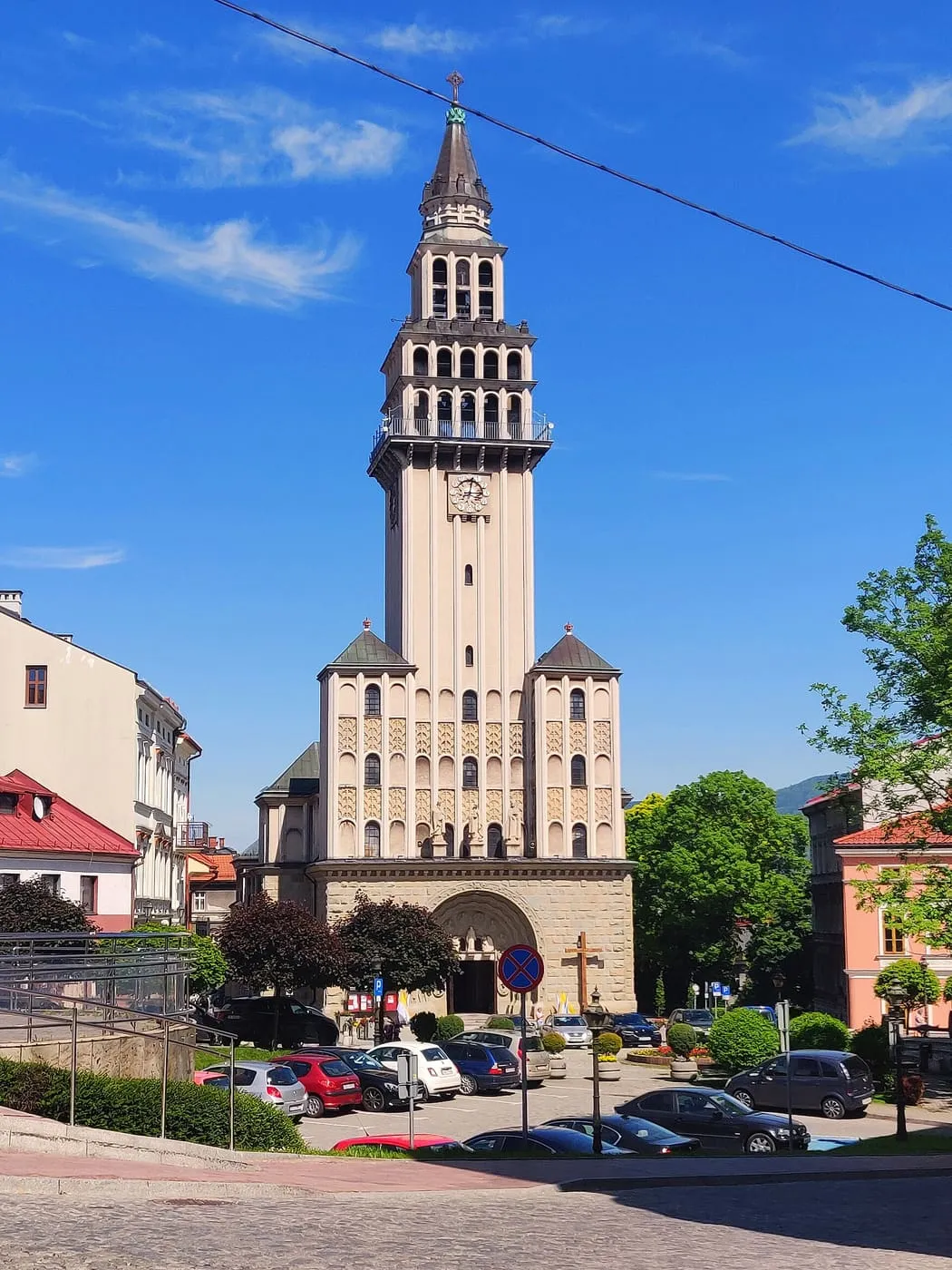 Smukła, kamienna wieża katedry św. Mikołaja w Bielsku-Białej z zegarem i arkadowymi kondygnacjami