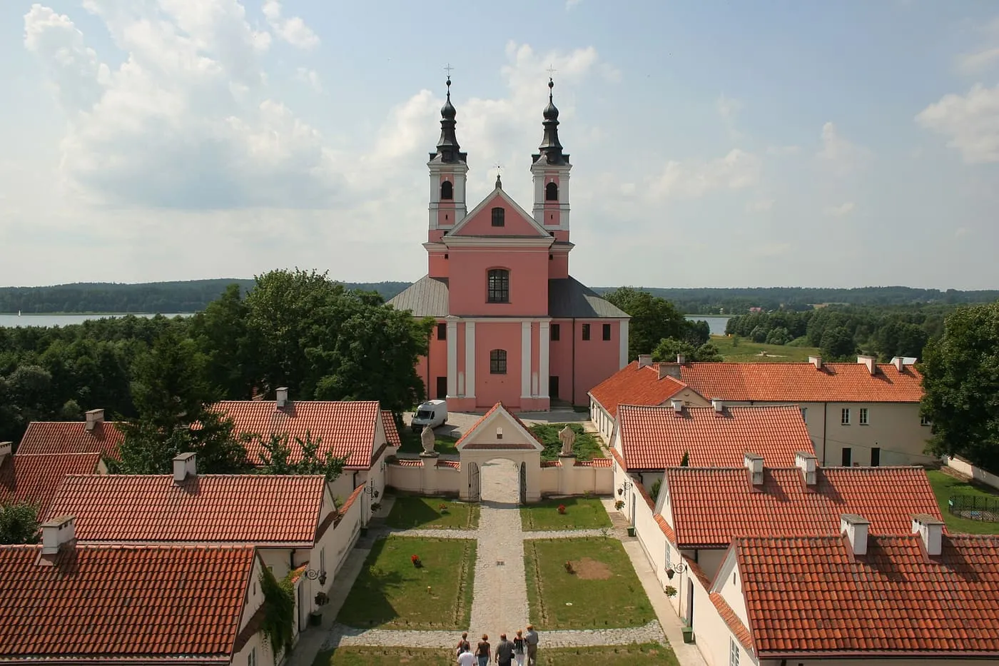 Różowy, barokowy kościół pokamedulski na półwyspie jeziora Wigry, otoczony zabudowaniami klasztornymi