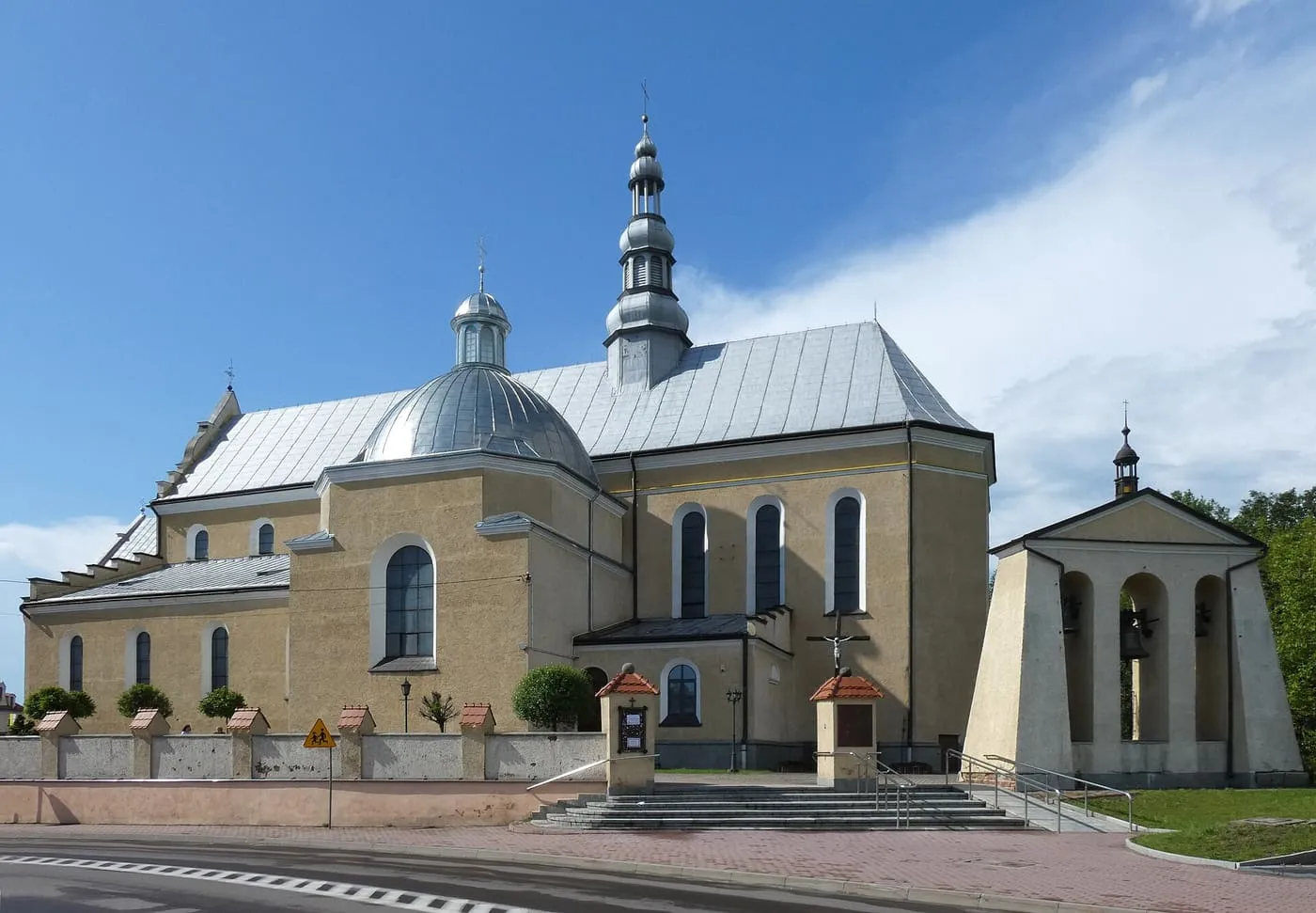 Kolegiata Wszystkich Świętych w Kolbuszowej z dużą, srebrną kopułą i smukłą iglicą, obok osobno stojącej dzwonnicy z widocznymi dzwonami