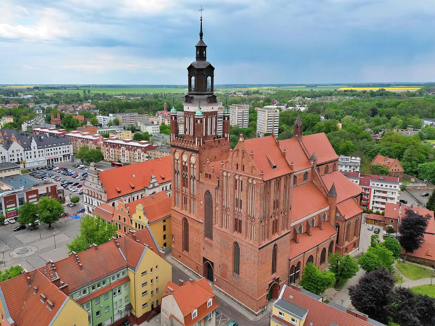 Widok z lotu ptaka na ceglaną, gotycką kolegiatę w Stargardzie z masywną wieżą i czerwonymi dachami