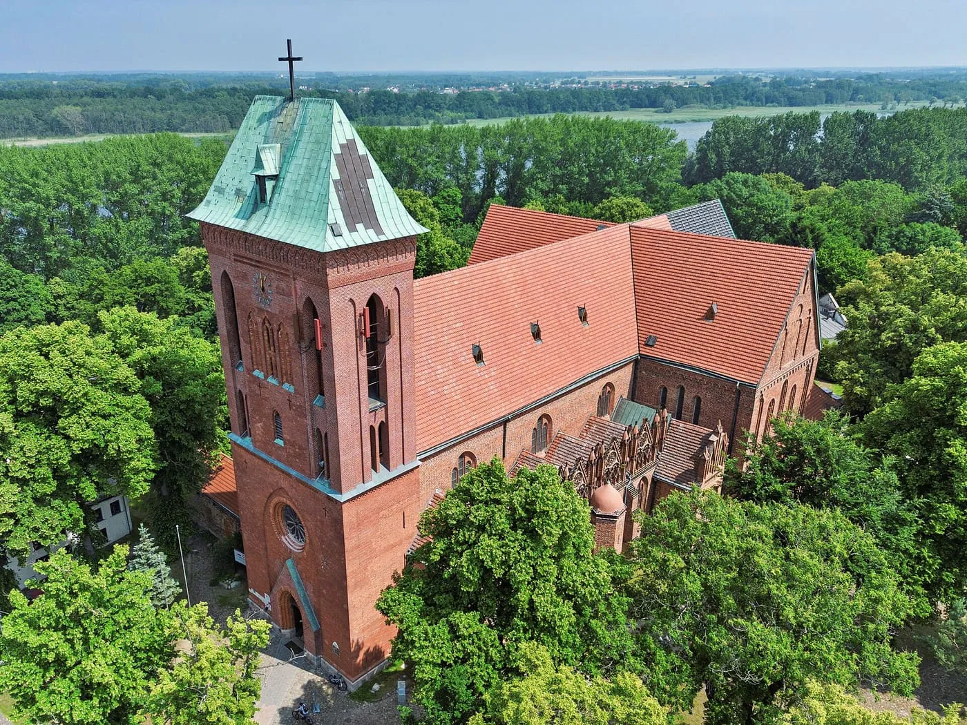 Gotycka konkatedra w Kamieniu Pomorskim z lotu ptaka, z wieżą krytą zieloną blachą, wśród zieleni nad rzeką