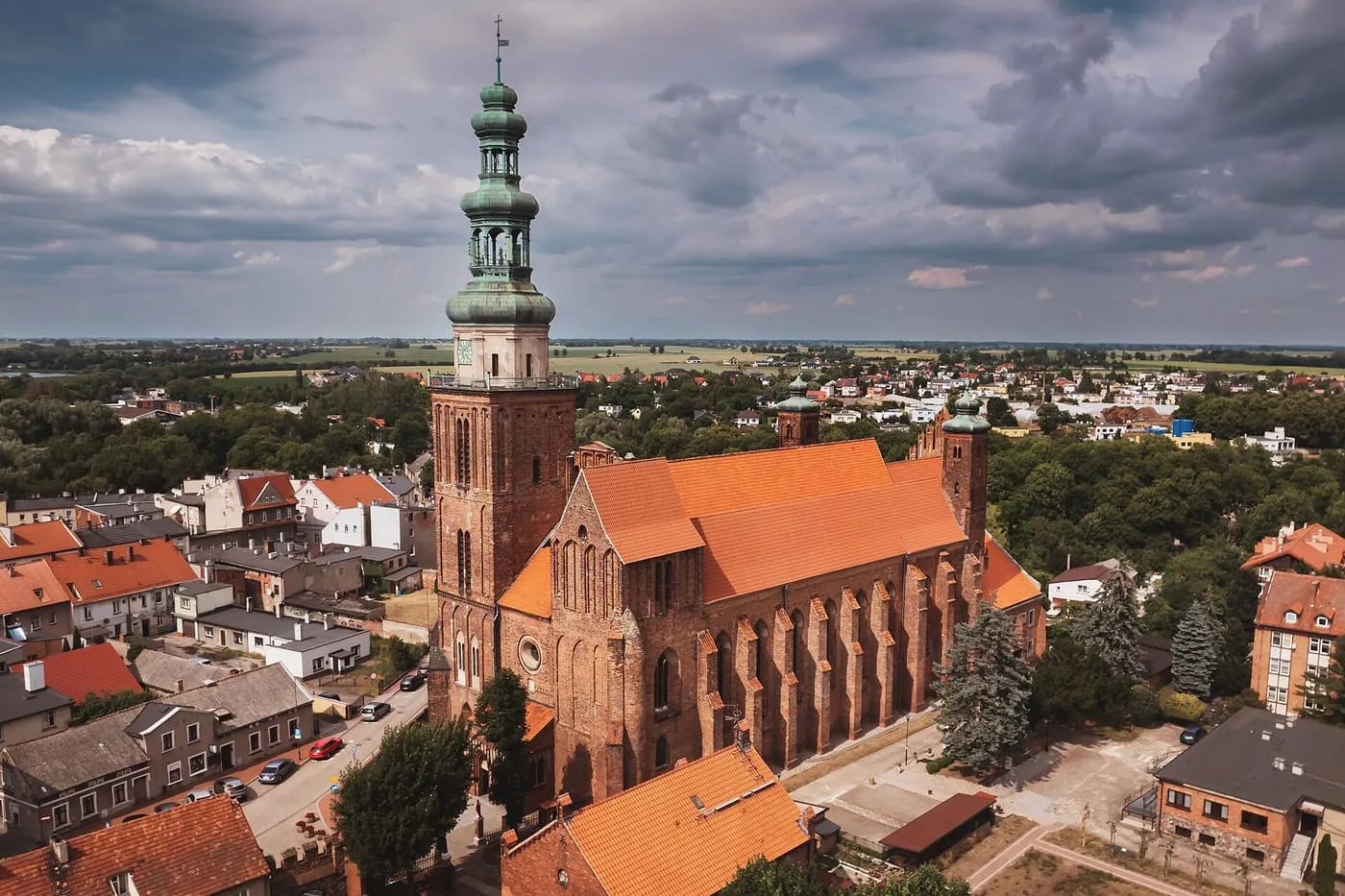 Gotycka, ceglana konkatedra w Chełmży z lotu ptaka, z wysoką wieżą zwieńczoną zielonym, wielokondygnacyjnym barokowym hełmem i przyporami wzdłuż nawy, nad dachami miasta