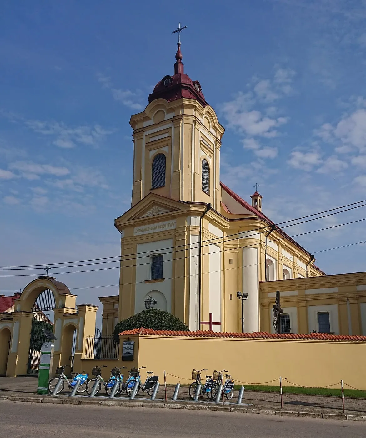 Kremowy, późnobarokowy kościół podominikański w Choroszczy z wieżą zwieńczoną bordowym hełmem i napisem „Dom mój-dom modlitwy” na fasadzie