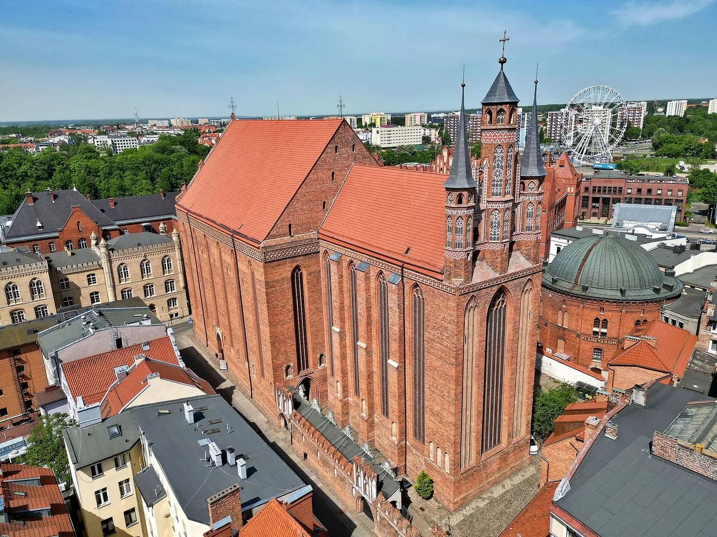 Widok z lotu ptaka na gotycki kościół Mariacki w Toruniu z ażurowymi, ceglanymi wieżyczkami