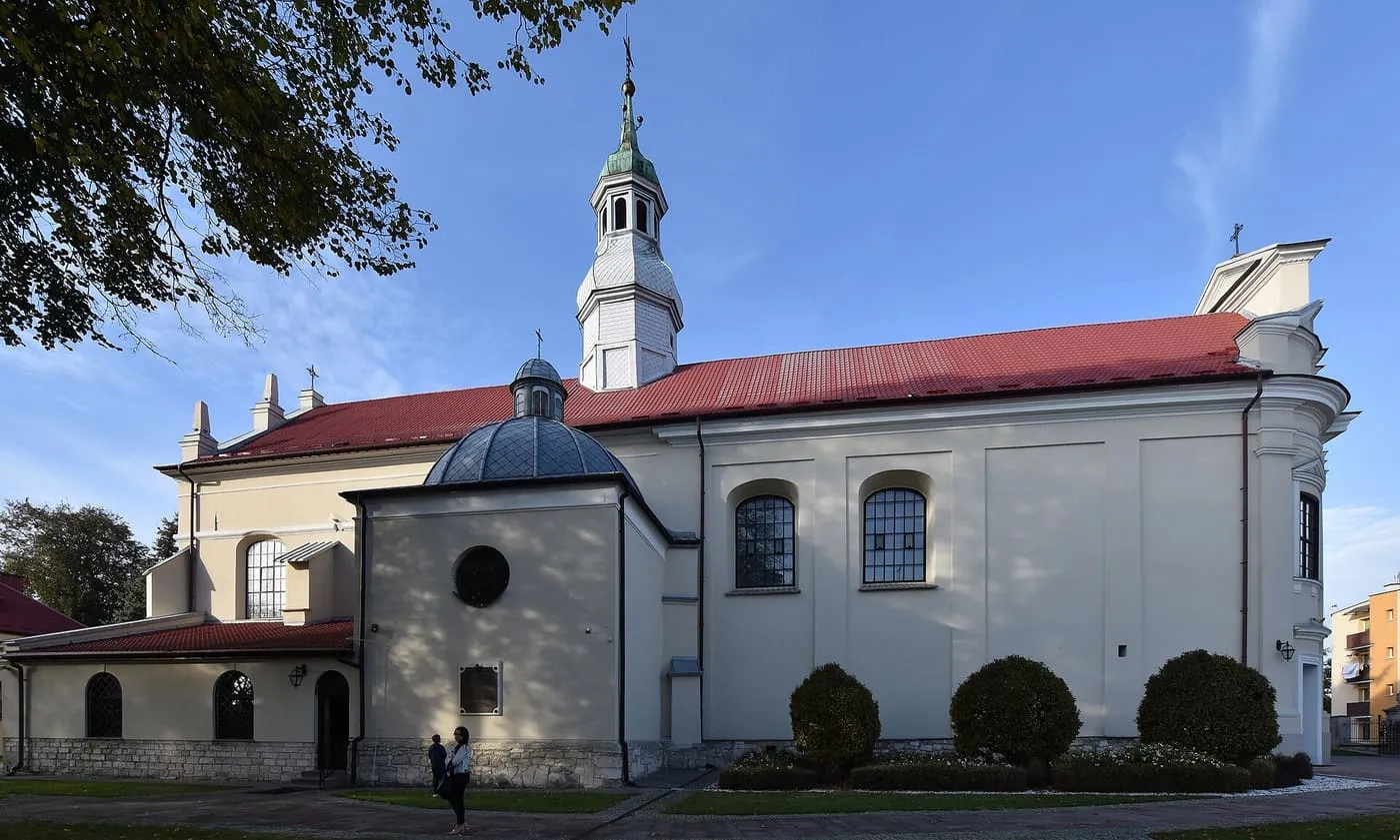 Kremowy, barokowy kościół Niepokalanego Poczęcia NMP w Busku-Zdroju z białą wieżą zwieńczoną zieloną kopułą