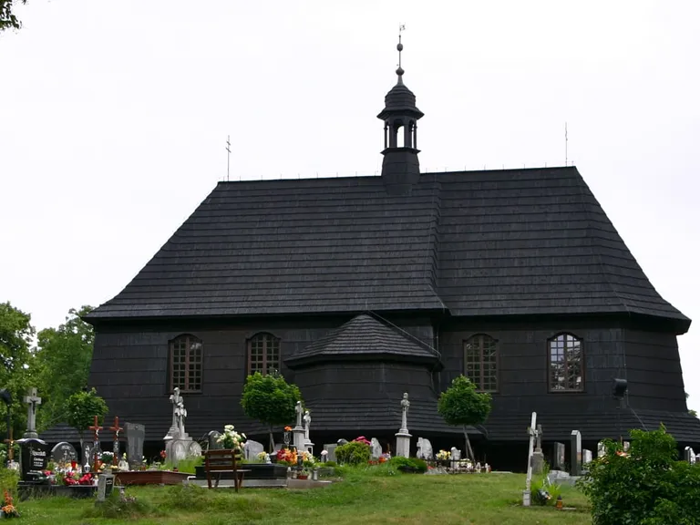 Czarny, drewniany kościół cmentarny św. Anny w Czarnowąsach, otoczony nagrobkami