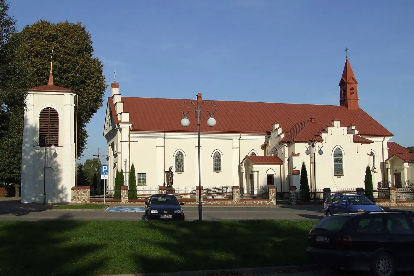Kremowy kościół św. Anny w Kolnie z czerwonym dachem, obok osobno stojącej, białej dzwonnicy