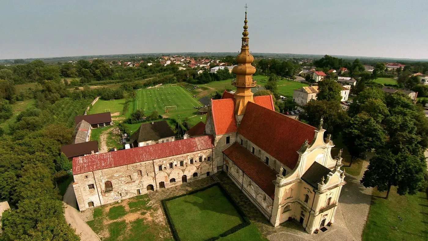 Widok z lotu ptaka na zespół pocysterski w Koprzywnicy — kościół św. Floriana ze złotą, barokową wieżą i przylegające skrzydło dawnego klasztoru