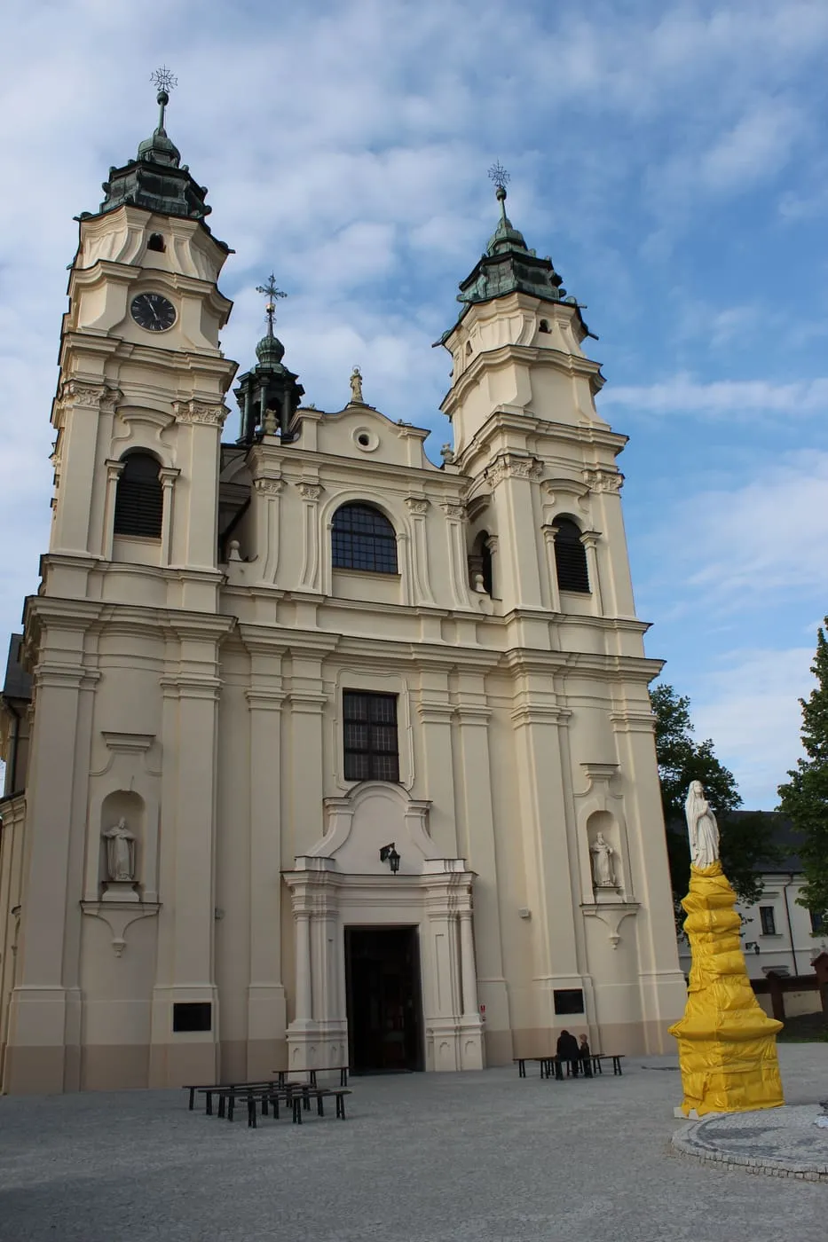 Kremowa, barokowa fasada kościoła św. Ludwika we Włodawie z dwiema wieżami zwieńczonymi ozdobnymi hełmami