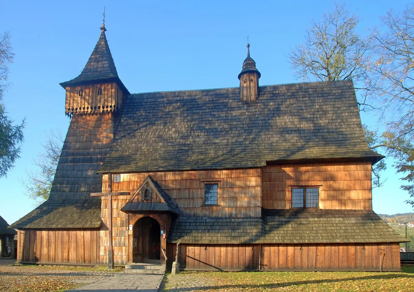 Drewniany kościół św. Michała Archanioła w Dębnie ze smukłą wieżą-dzwonnicą, jesienią