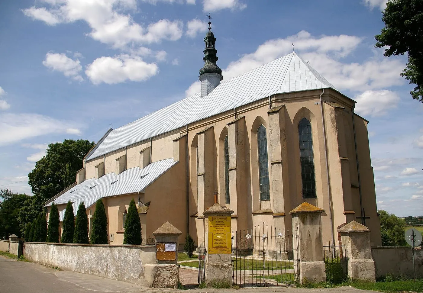 Gotycki kościół w Bodzentynie z wysoką, ośmioboczną wieżą zwieńczoną hełmem, otoczony murem