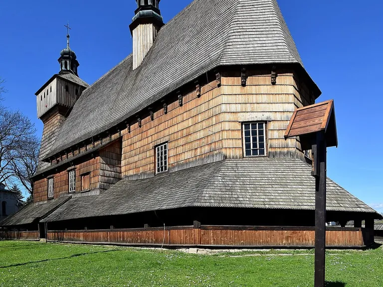Drewniany kościół w Haczowie z ogromnym, stromym dachem krytym gontem i małą wieżyczką z cebulastym hełmem