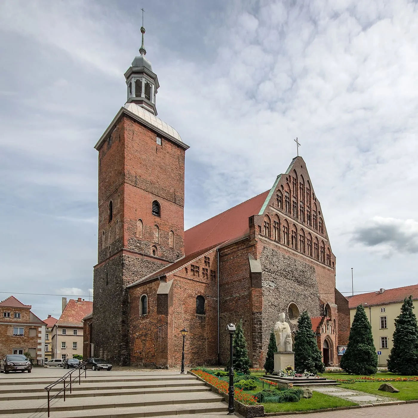 Gotycki kościół w Szprotawie z wysoką, ceglaną wieżą na kamiennej podstawie