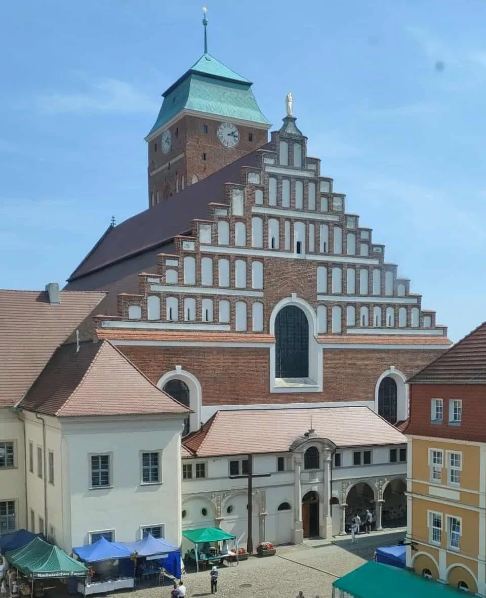 Kościół w Żaganiu ze schodkowym szczytem, wieżą zegarową i renesansową arkadową loggią u podstawy
