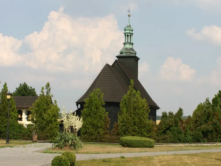 Drewniana, kryta gontem kaplica św. Franciszka ustawiona na dachu murowanego kościoła w Malni, z cebulastą wieżyczką