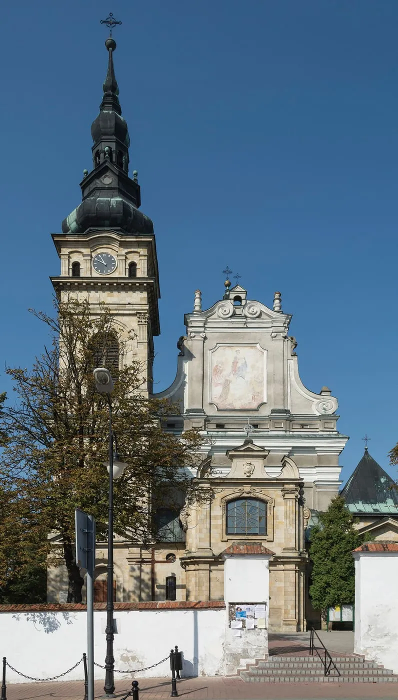 Barokowa fasada sanktuarium w Tarnobrzegu-Dzikowie z wysoką wieżą zegarową i freskiem Matki Bożej w szczycie