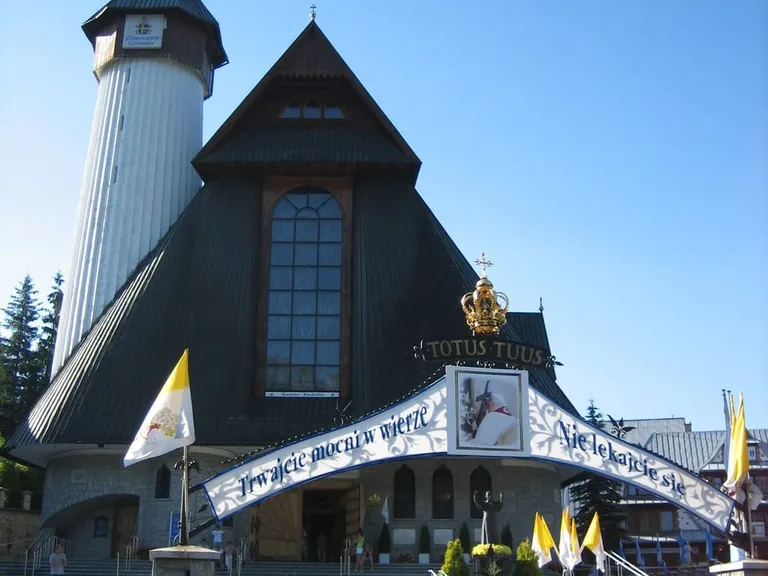 Sanktuarium Matki Bożej Fatimskiej w Zakopanem z charakterystycznym, stromym dachem i białą wieżą zwieńczoną koroną, związane z kultem Jana Pawła II