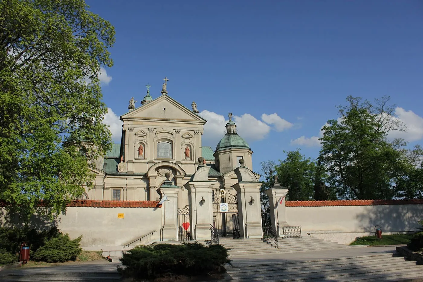 Barokowa fasada sanktuarium w Studziannie z ozdobną bramą wjazdową i figurami świętych