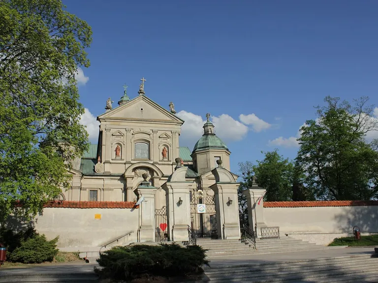 Barokowa fasada sanktuarium w Studziannie z ozdobną bramą wjazdową i figurami świętych